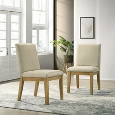 two beige chairs sitting on top of a rug