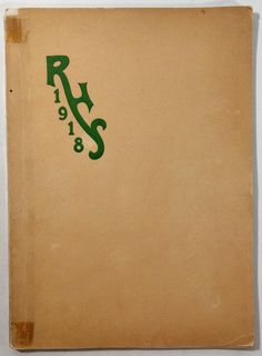 an old brown book with green lettering on the front and back cover, sitting on a white surface