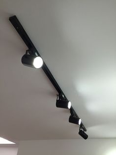 three spotlights are hanging from the ceiling in a room with white walls and flooring