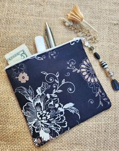 a purse with a pen and money on it sitting on a burlap surface