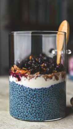 a blueberry and yogurt parfait in a glass with a wooden spoon