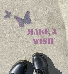 a pair of black shoes standing in front of a sidewalk with the words make a wish painted on it