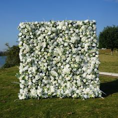 a large white flowered structure sitting on top of a lush green field