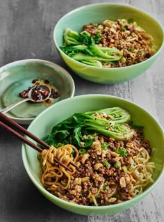 two green bowls filled with noodles and vegetables