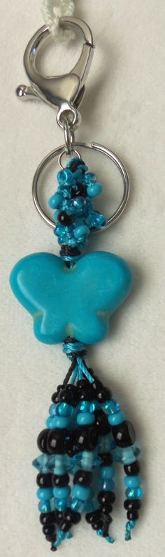 a blue beaded keychain hanging from a metal hook on a white surface