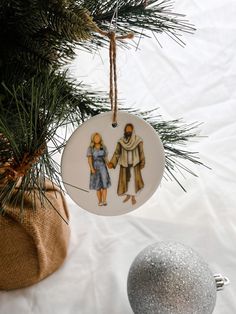 an ornament hanging from a christmas tree next to a silver bauble