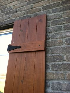 an open wooden door on the side of a brick building next to a white window