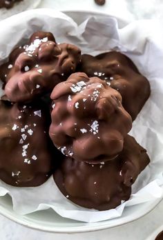 chocolate covered donuts with white sprinkles in a paper wrapper on a plate