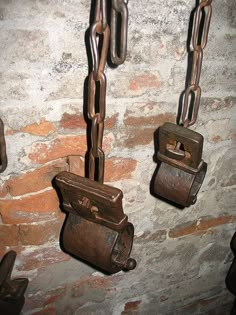 three rusty metal chains hanging from the side of a brick wall next to a toilet paper dispenser