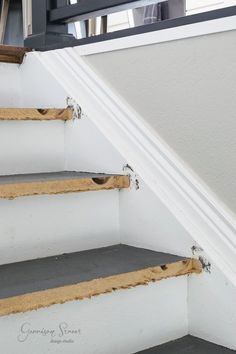 the bottom part of a staircase that has been stripped off and painted white with brown trim