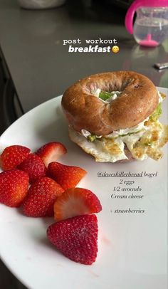 a bagel sandwich and strawberries on a white plate