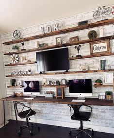 a desk with two computer monitors on top of it next to a wall mounted bike