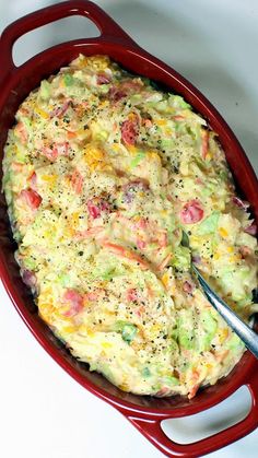 a red casserole dish with broccoli and other food items in it