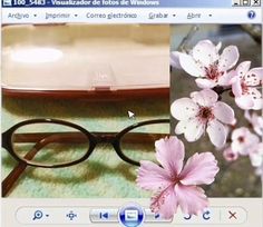 a pair of glasses sitting on top of a table next to pink flowers and a laptop computer