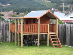 there is a small wooden house with bicycles parked in the yard next to it and an ad for the back porch