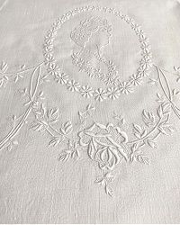 an embroidered tablecloth with flowers and leaves on white linen, in the shape of a circle