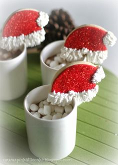 three cups filled with marshmallows and santa hats