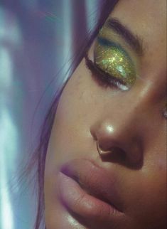 a woman with green and gold eye makeup