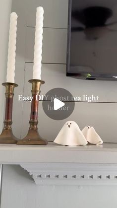 two candles sitting on top of a mantle with ghost figurines next to it