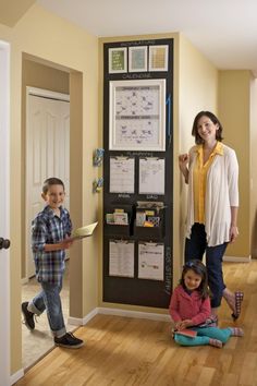 a woman and two children standing in front of a bulletin board