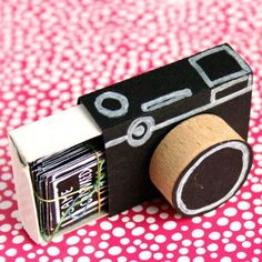 a camera made out of cardboard sitting on top of a pink and white tablecloth