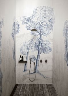 a bathroom with trees painted on the wall and shower head in the corner, along with two soap dispensers