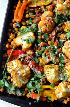 a black tray filled with vegetables and chickpeas