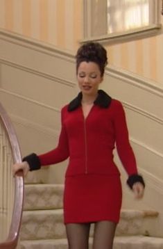 a woman in a red dress and black tights is walking down the stairs with her hands on her hips