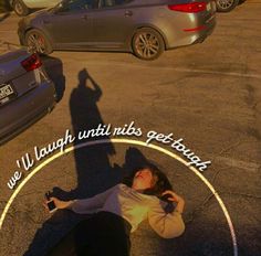 a woman laying on the ground in front of a parking lot next to parked cars