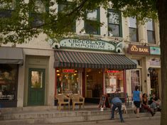 people are walking down the sidewalk in front of a chocolate emporum