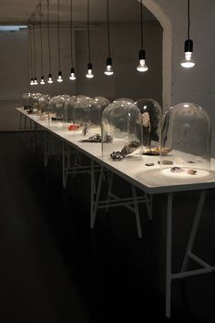 a long table with several glass domes on top and lights hanging from the ceiling above it