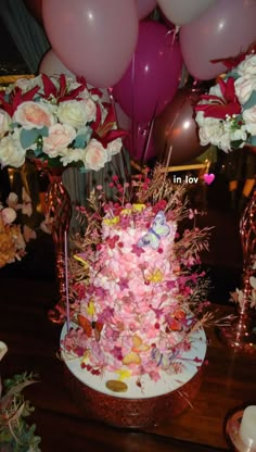 there is a cake with flowers and balloons on the table