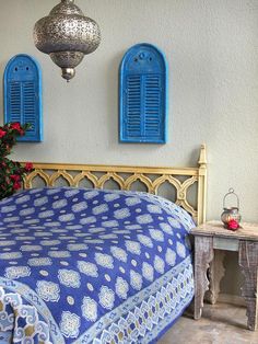 a bedroom with blue shutters and a bed in front of a planter filled with red flowers