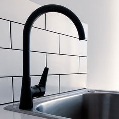 a black faucet sitting on top of a kitchen sink next to a white tiled wall