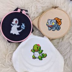 three cross stitched items are sitting on a furry surface