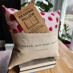 a pillow sitting on top of a wooden table next to a book and some books