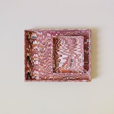 a pink tray with an abstract design on the front and sides, sitting on a white surface