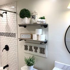 a bathroom with white tile walls and shelves filled with toilet paper, plants and other items