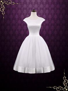 a white dress on a mannequin stand in front of a purple wall with ornate ornaments