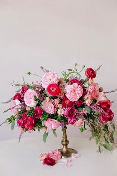 a vase filled with pink and red flowers on top of a white table next to a pair of scissors