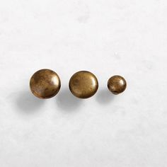 two brass knobs on a white surface