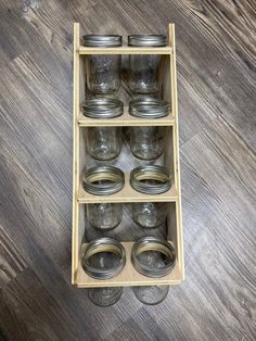 a wooden shelf filled with glass jars on top of a hard wood floor