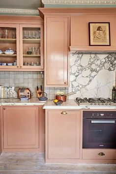 a kitchen with pink cabinets and marble counter tops