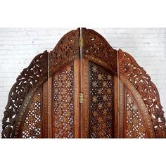 an ornate wooden door with intricate carvings on the front and side panels, set against a white brick wall