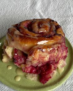 a green plate topped with a pastry covered in icing and toppings on top of a white table cloth