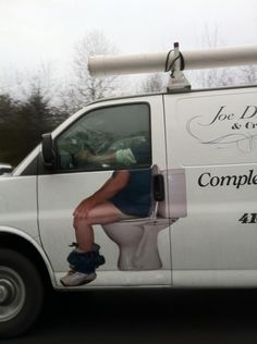 a white van is parked on the side of the road with a woman sitting on the toilet