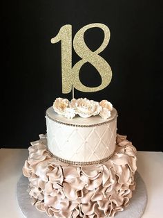 there is a white cake with gold numbers on the top and ruffles around it