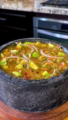 a bowl of soup sitting on top of a wooden table next to an oven and counter