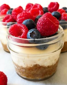 mini mason jar cheesecakes with raspberries and blueberries in the background