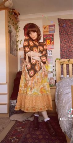 a woman standing in a bedroom wearing a long dress and black booties with her hair pulled back